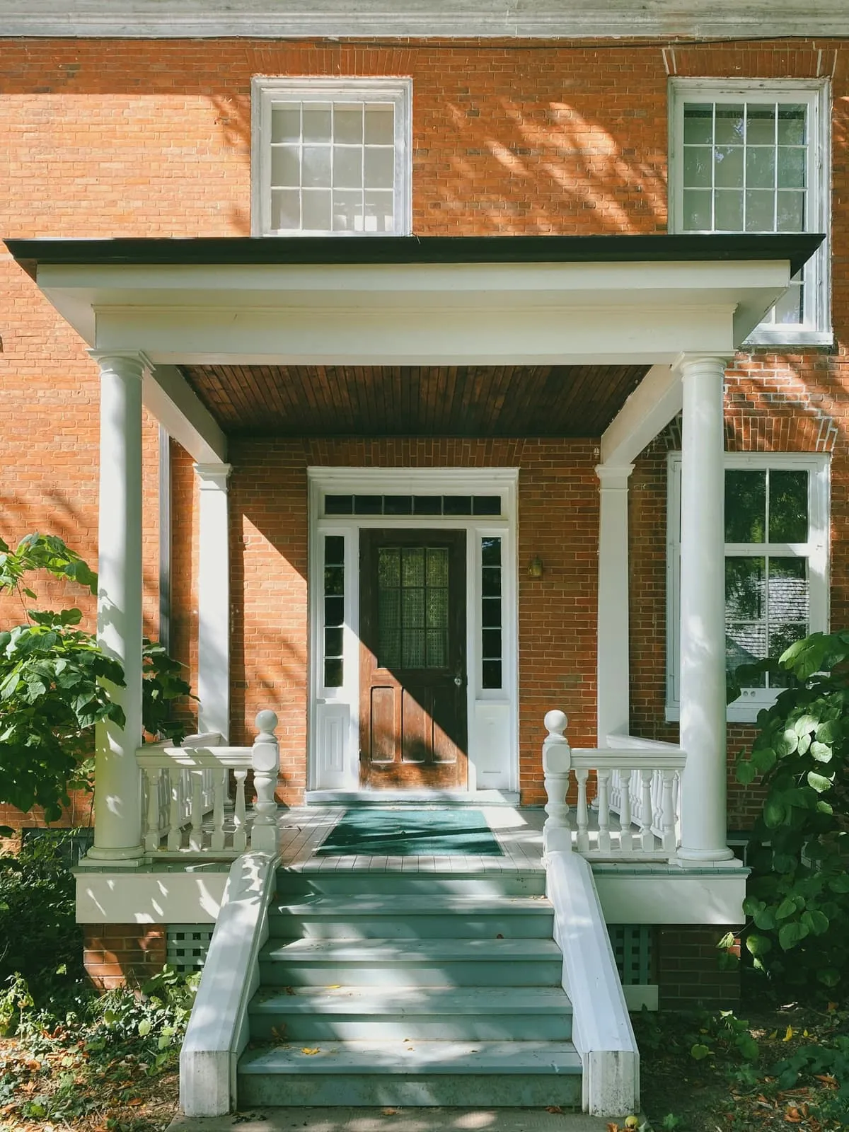 Red brick period house with a white front door and portico