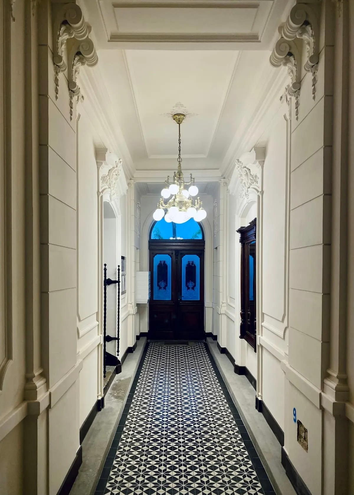 Period hallway with patterned tiled floor and a panelled front door